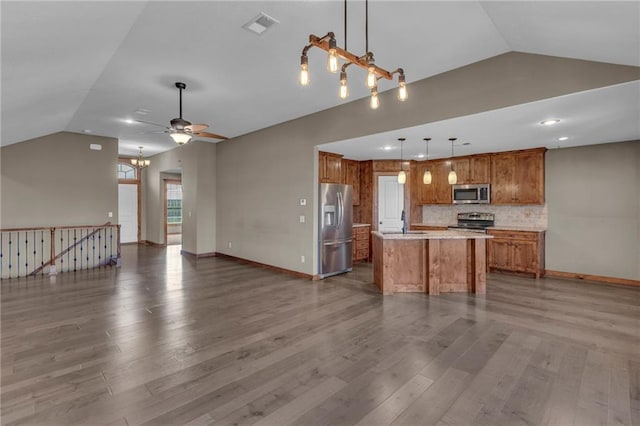 kitchen with brown cabinets, stainless steel appliances, open floor plan, visible vents, and lofted ceiling
