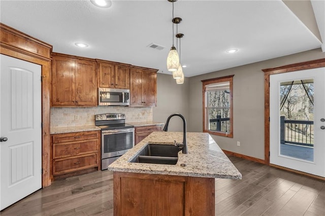 kitchen featuring a sink, appliances with stainless steel finishes, wood finished floors, and visible vents