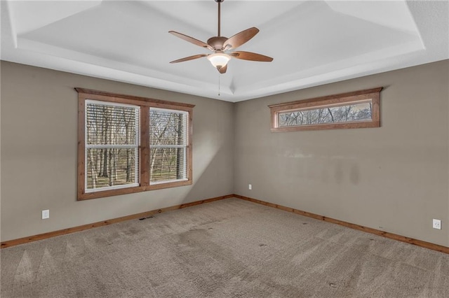 carpeted empty room with a raised ceiling and baseboards