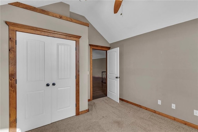 unfurnished bedroom with carpet floors, a closet, vaulted ceiling, baseboards, and a ceiling fan