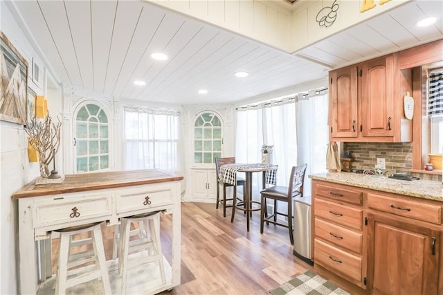 kitchen with backsplash, light wood-style flooring, recessed lighting, and light stone countertops