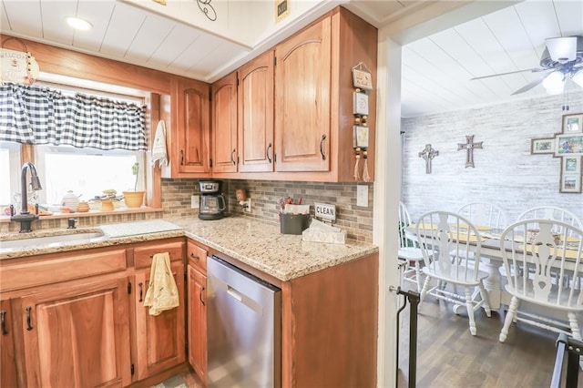 kitchen with a sink, decorative backsplash, wood finished floors, stainless steel dishwasher, and light stone counters