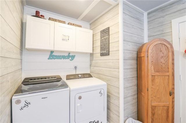laundry room featuring wood walls, independent washer and dryer, and cabinet space