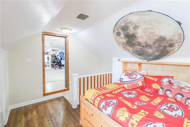 bedroom with dark wood-type flooring, visible vents, baseboards, and vaulted ceiling
