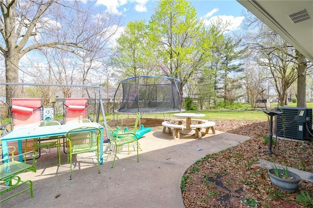view of patio / terrace featuring cooling unit, a trampoline, outdoor dining area, and visible vents