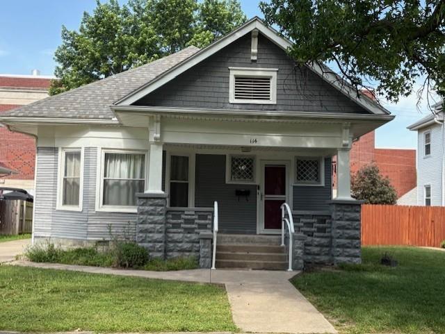 bungalow-style home featuring a porch, stone siding, and a shingled roof