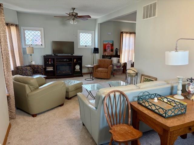 living area with ceiling fan and light carpet