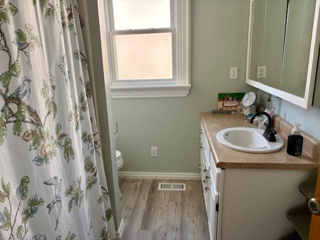 bathroom featuring wood finished floors, vanity, toilet, and baseboards
