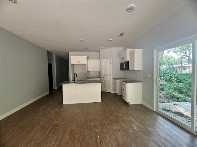 320 E 2nd St, Adrian, MO 64720 - kitchen featuring dark countertops, appliances with stainless steel finishes, dark wood-type flooring, backsplash, and a center island with sink