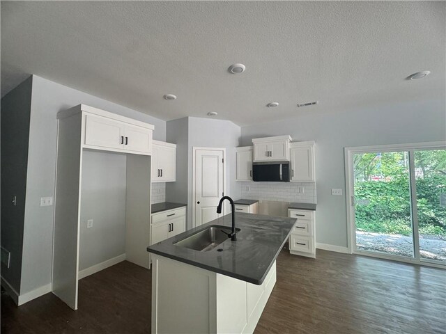 320 E 2nd St, Adrian, MO 64720 - kitchen featuring stainless steel microwave, backsplash, dark countertops, a textured ceiling, and white cabinetry