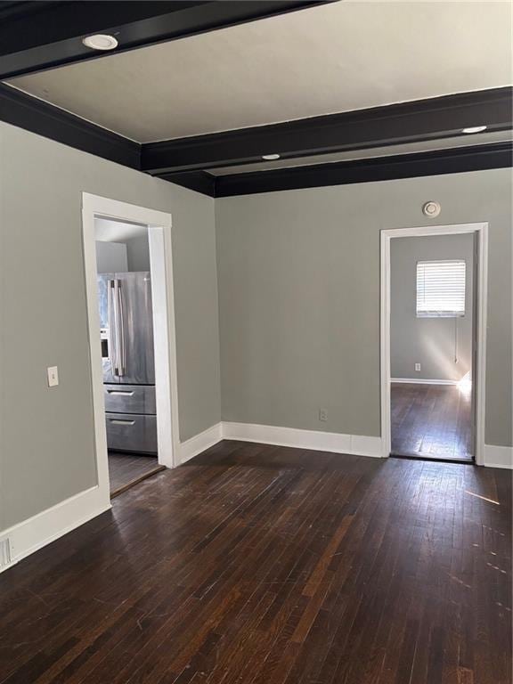 spare room with baseboards, beam ceiling, and dark wood-style flooring
