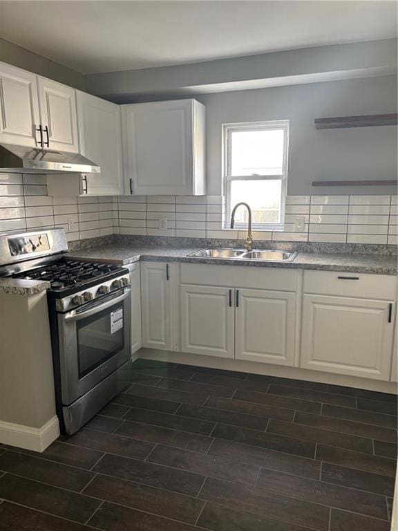 kitchen with stainless steel gas stove, a sink, white cabinetry, under cabinet range hood, and wood tiled floor