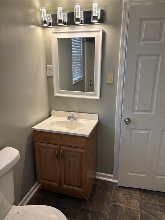 bathroom with toilet, vanity, and baseboards