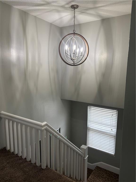 staircase with an inviting chandelier, carpet, and a textured ceiling