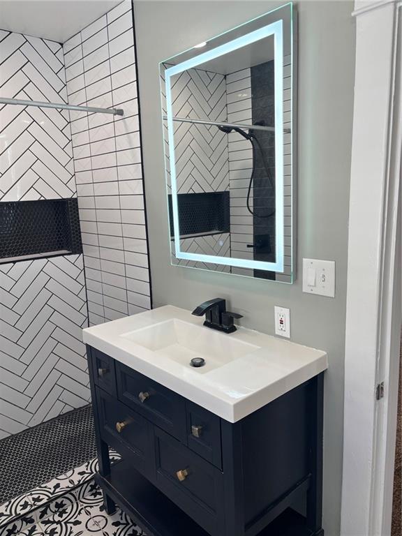 bathroom featuring tiled shower and vanity