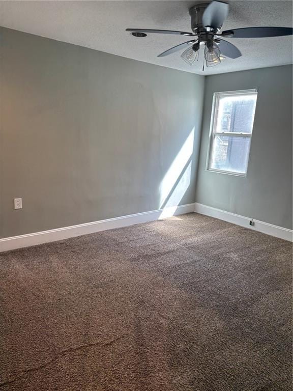 carpeted spare room featuring a textured ceiling, baseboards, and ceiling fan