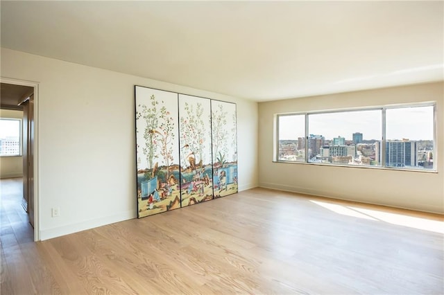 spare room featuring wood finished floors, healthy amount of natural light, and baseboards