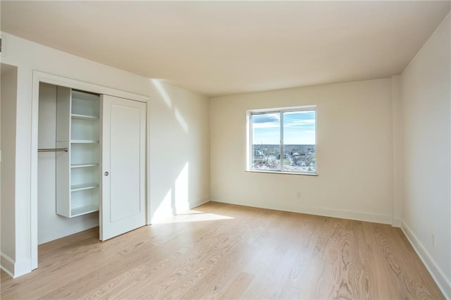 unfurnished bedroom with light wood-style floors, baseboards, and a closet