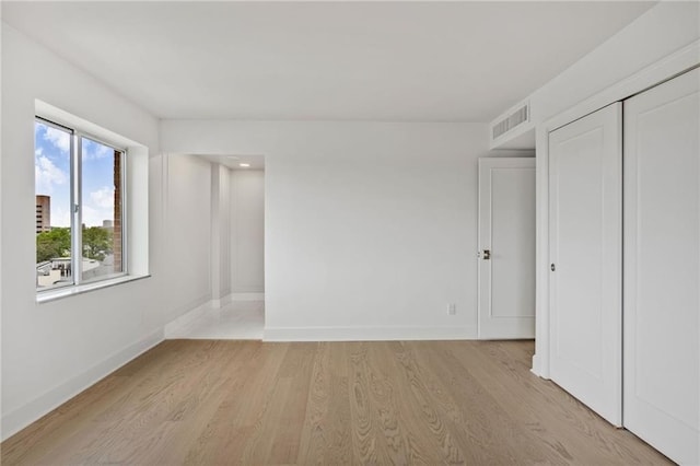 unfurnished bedroom featuring baseboards, light wood-type flooring, and a closet