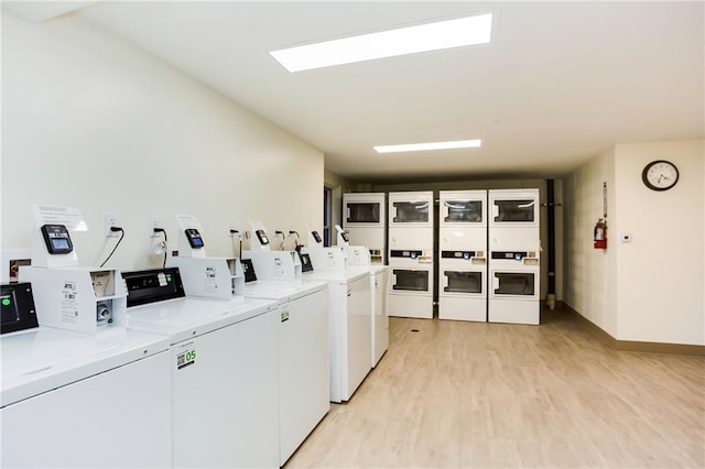 communal laundry room featuring independent washer and dryer, light wood-style floors, stacked washer / dryer, and baseboards
