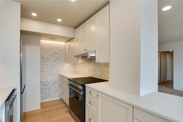 kitchen with electric range, under cabinet range hood, light countertops, white cabinets, and recessed lighting