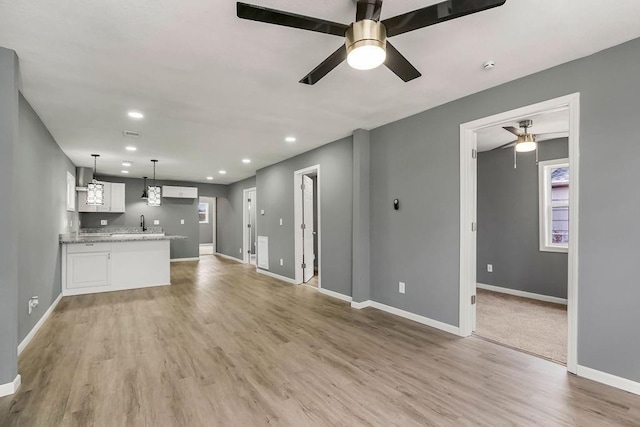 unfurnished living room with baseboards, ceiling fan, and light wood finished floors
