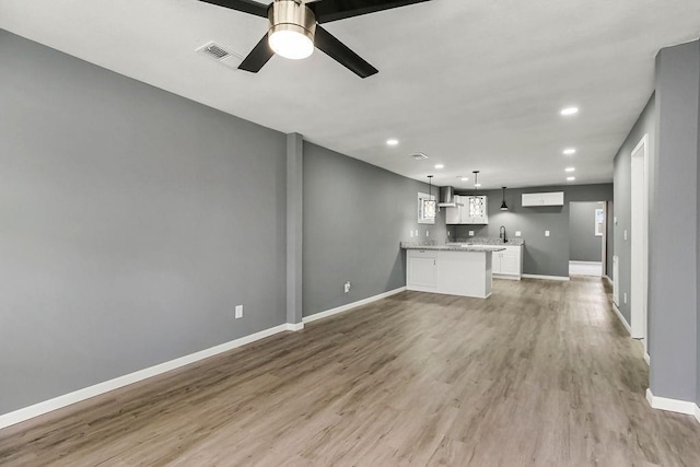 unfurnished living room featuring a ceiling fan, light wood-style flooring, baseboards, and visible vents