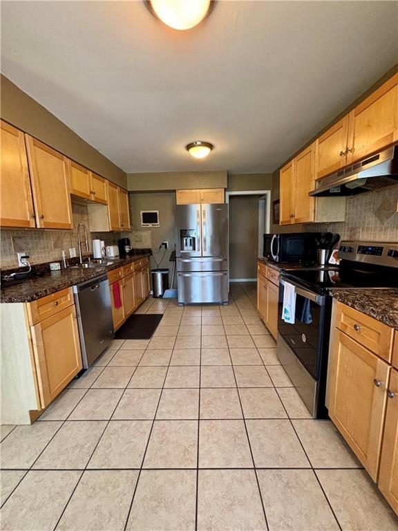 1519 Niagara St, Burlington, KS 66839 - kitchen featuring a sink, backsplash, under cabinet range hood, light tile patterned floors, and stainless steel appliances