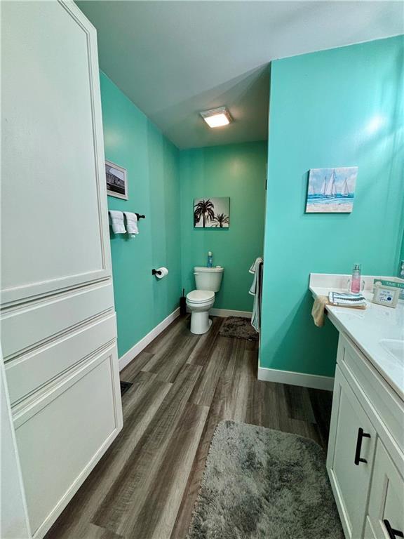 1519 Niagara St, Burlington, KS 66839 - bathroom with baseboards, toilet, vanity, and wood finished floors