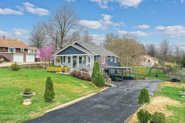 bungalow-style house featuring a front lawn, covered porch, and aphalt driveway