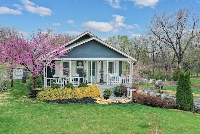 bungalow-style house featuring covered porch, fence, and a front lawn