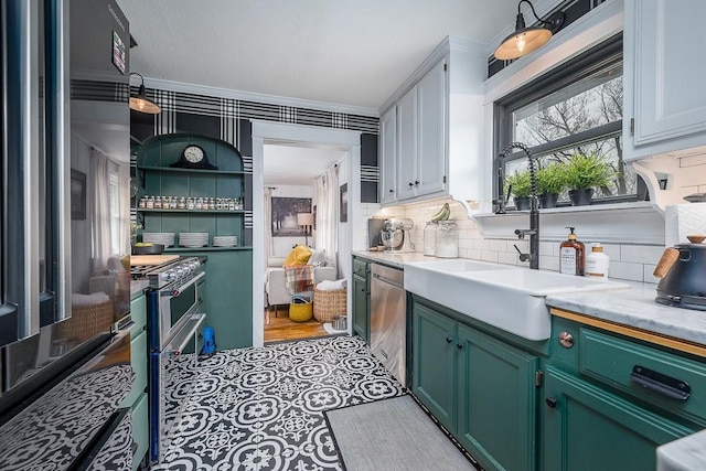 kitchen featuring green cabinetry, light countertops, a sink, decorative backsplash, and ornamental molding
