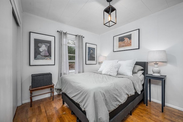 bedroom with hardwood / wood-style floors, ornamental molding, and baseboards