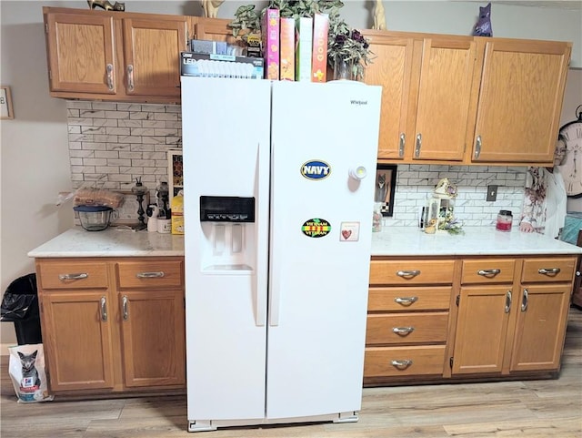 kitchen with light countertops, decorative backsplash, light wood finished floors, and white fridge with ice dispenser