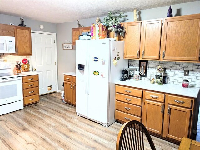1804 S Phillips St, El Dorado Springs, MO 64744 - kitchen with white appliances, light wood-style floors, light countertops, a textured ceiling, and backsplash