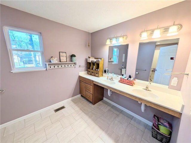 bathroom featuring double vanity, baseboards, visible vents, and a sink