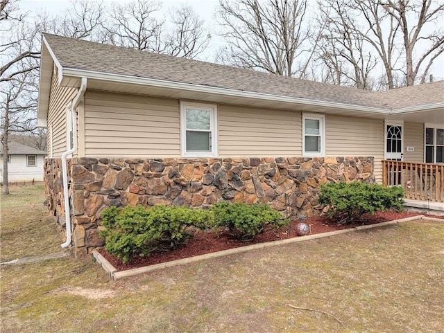 view of home's exterior with a shingled roof and stone siding