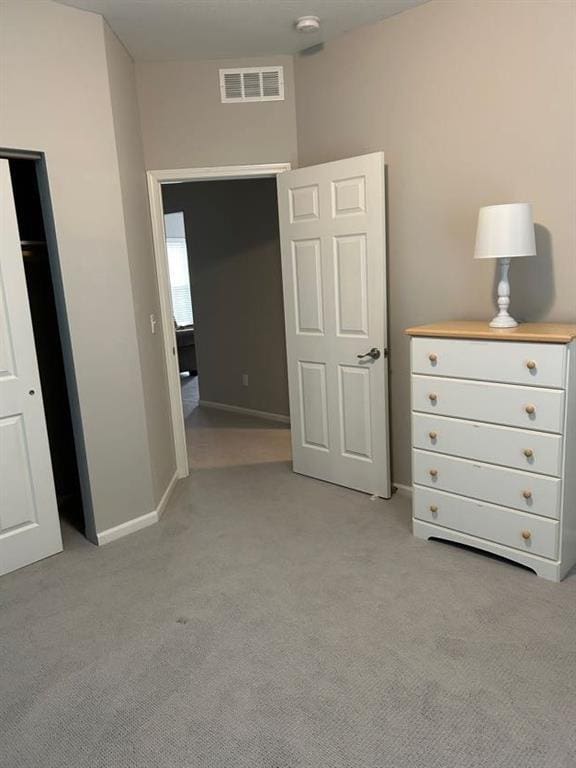 unfurnished bedroom with baseboards, light colored carpet, and visible vents