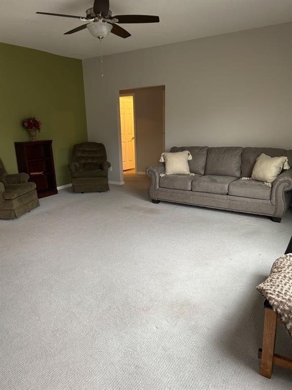 carpeted living room with baseboards and ceiling fan