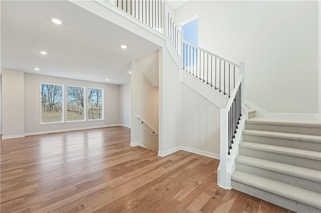 503 Woodview Dr, Raymore, MO 64083 - unfurnished living room with wood finished floors, stairway, baseboards, and recessed lighting