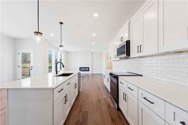 503 Woodview Dr, Raymore, MO 64083 - kitchen with a sink, appliances with stainless steel finishes, dark wood-style flooring, tasteful backsplash, and light countertops