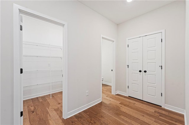 503 Woodview Dr, Raymore, MO 64083 - unfurnished bedroom with a closet, wood finished floors, and baseboards
