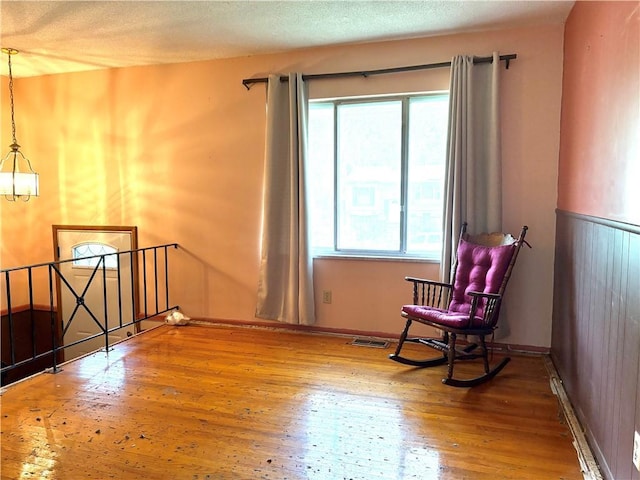 living area featuring visible vents, wood finished floors, a healthy amount of sunlight, and an upstairs landing