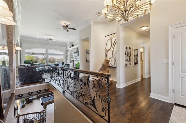 hallway featuring a notable chandelier, wood-type flooring, baseboards, and crown molding