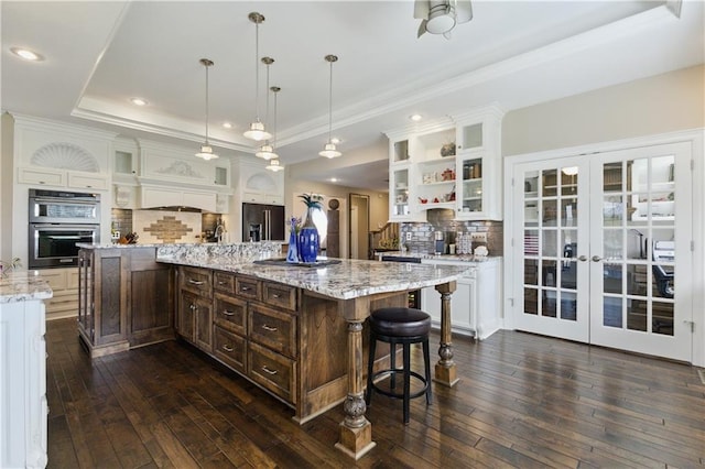 kitchen with a tray ceiling, high end black refrigerator, white cabinetry, and double oven