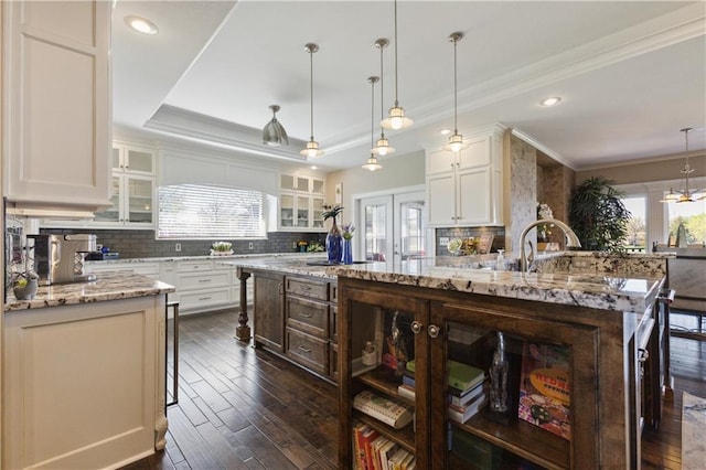 kitchen featuring dark wood-style floors, tasteful backsplash, and a center island with sink
