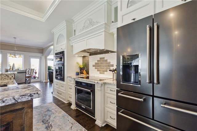 kitchen featuring high end fridge, black electric cooktop, ornamental molding, light stone countertops, and decorative columns