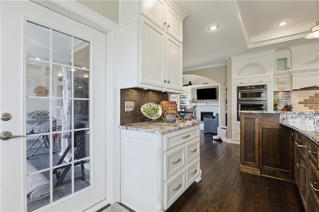 kitchen featuring decorative backsplash, light stone countertops, dark wood-type flooring, and white cabinets