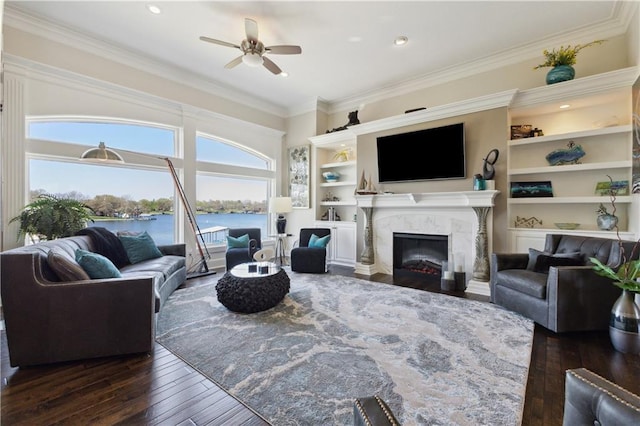 living area featuring ceiling fan, a premium fireplace, ornamental molding, dark wood-type flooring, and recessed lighting