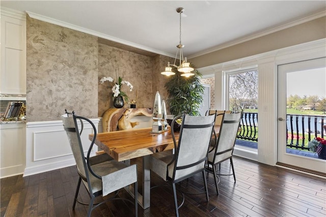 dining room featuring a notable chandelier, dark wood finished floors, crown molding, and a wainscoted wall